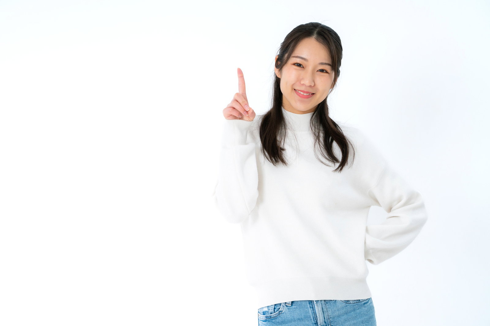 白背景で人差し指を立てて微笑む女性のポートレート［モデル：SAKI］