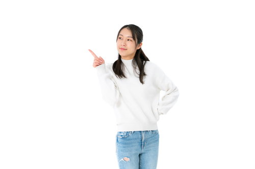 左上を指差す若い女性のポーズ、笑顔でジェスチャー