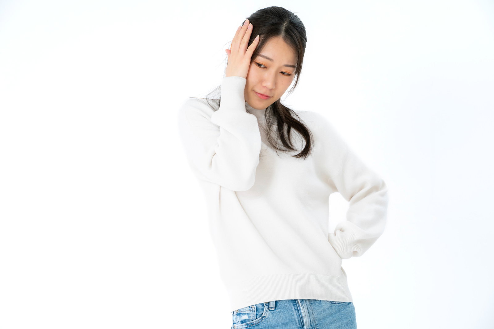 白いトップスを着た女性が両手で頭を抱えて困った表情をしている［モデル：SAKI］