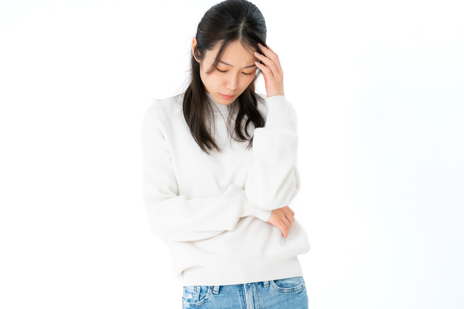 白背景でおでこを押えて俯く女性が疲労や困惑を表現する［モデル：SAKI］