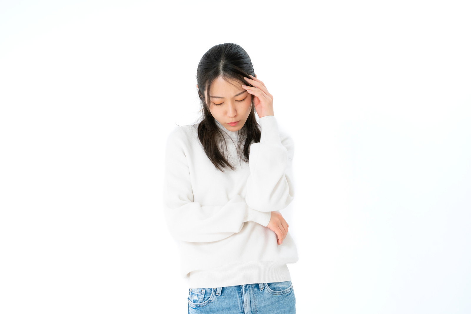 白い長袖を着た女性が右手で頭を押さえて悩んでいる様子［モデル：SAKI］