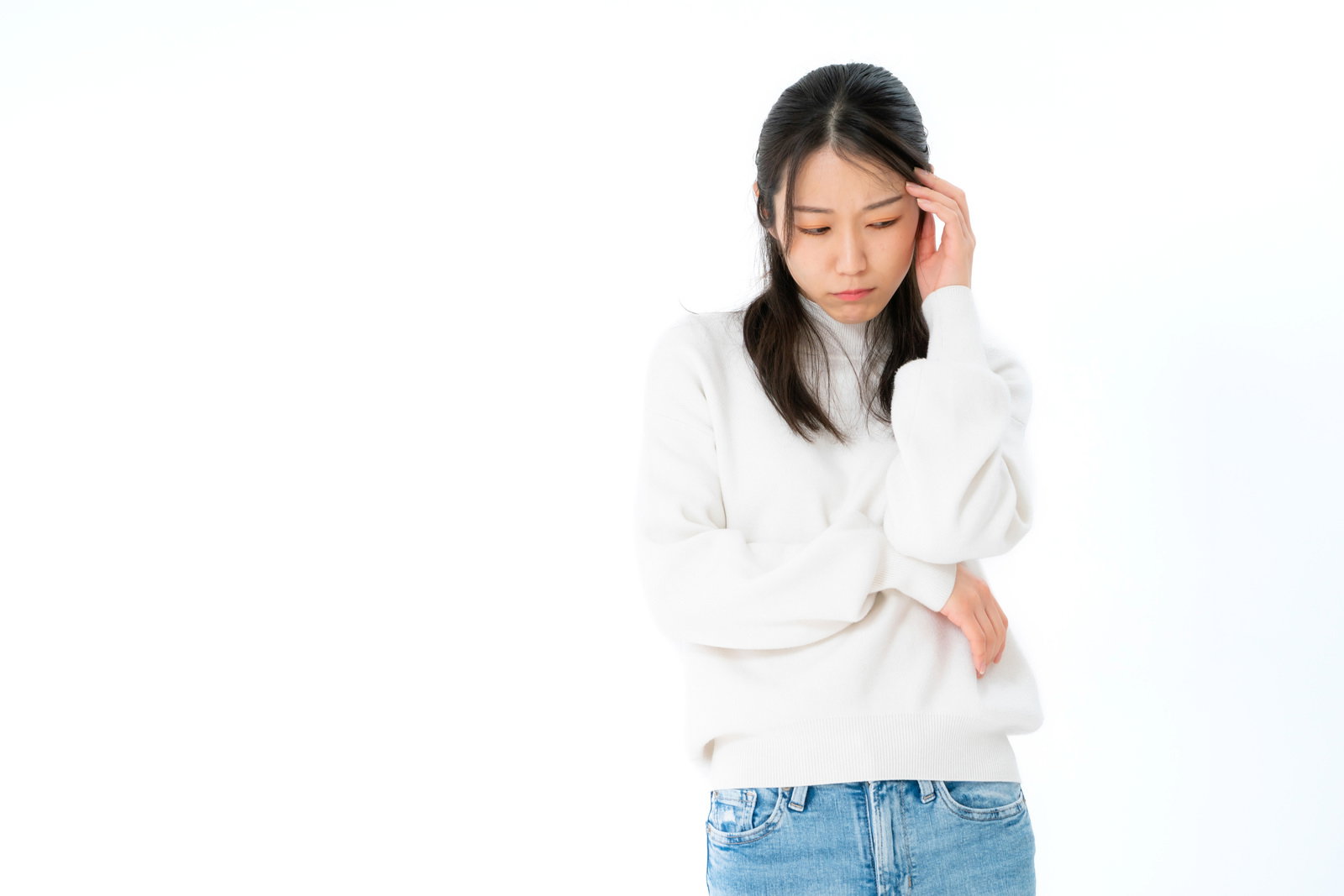 白い長袖シャツを着た女性がおでこを押さえて困惑している様子［モデル：SAKI］