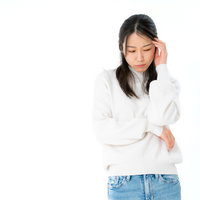 おでこを押さえて困惑する女性のポーズの写真