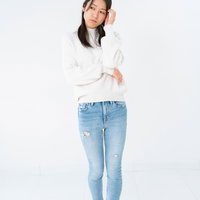 白いセーターを着た立ち上がって頭を抱える悩む女性のポーズの写真