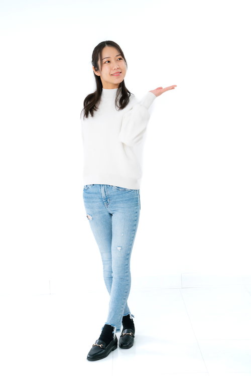 左手を説明するように広げる微笑む女性のポーズ