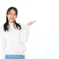 左手で案内する紹介ポーズをとる笑顔の女性の写真