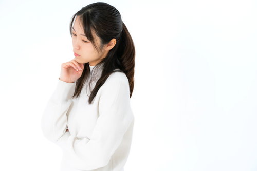 白背景で手を顎に当てて考え事をする女性のポートレート