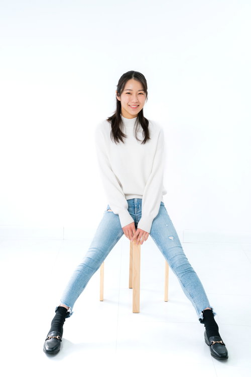 足を開いて腰掛けるカジュアルな笑顔の女性