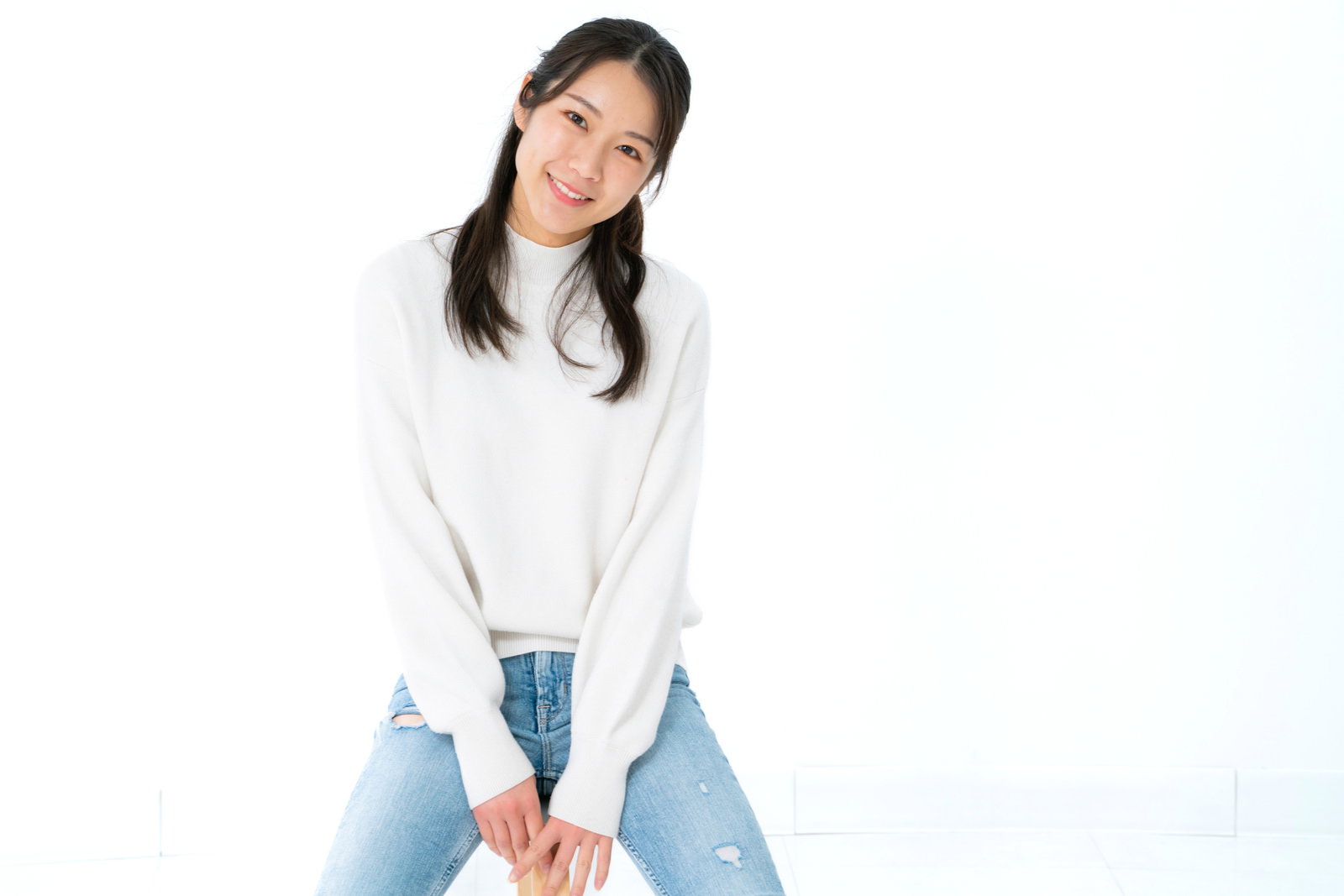 首をかしげながら笑顔でこちらを見つめる女性［モデル：SAKI］