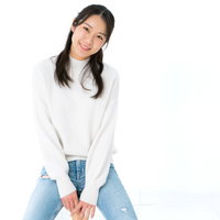 白背景で笑顔で腰を掛ける女性のポートレートの写真