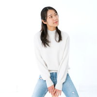 白背景で外方を向いて着席する女性のポーズの写真