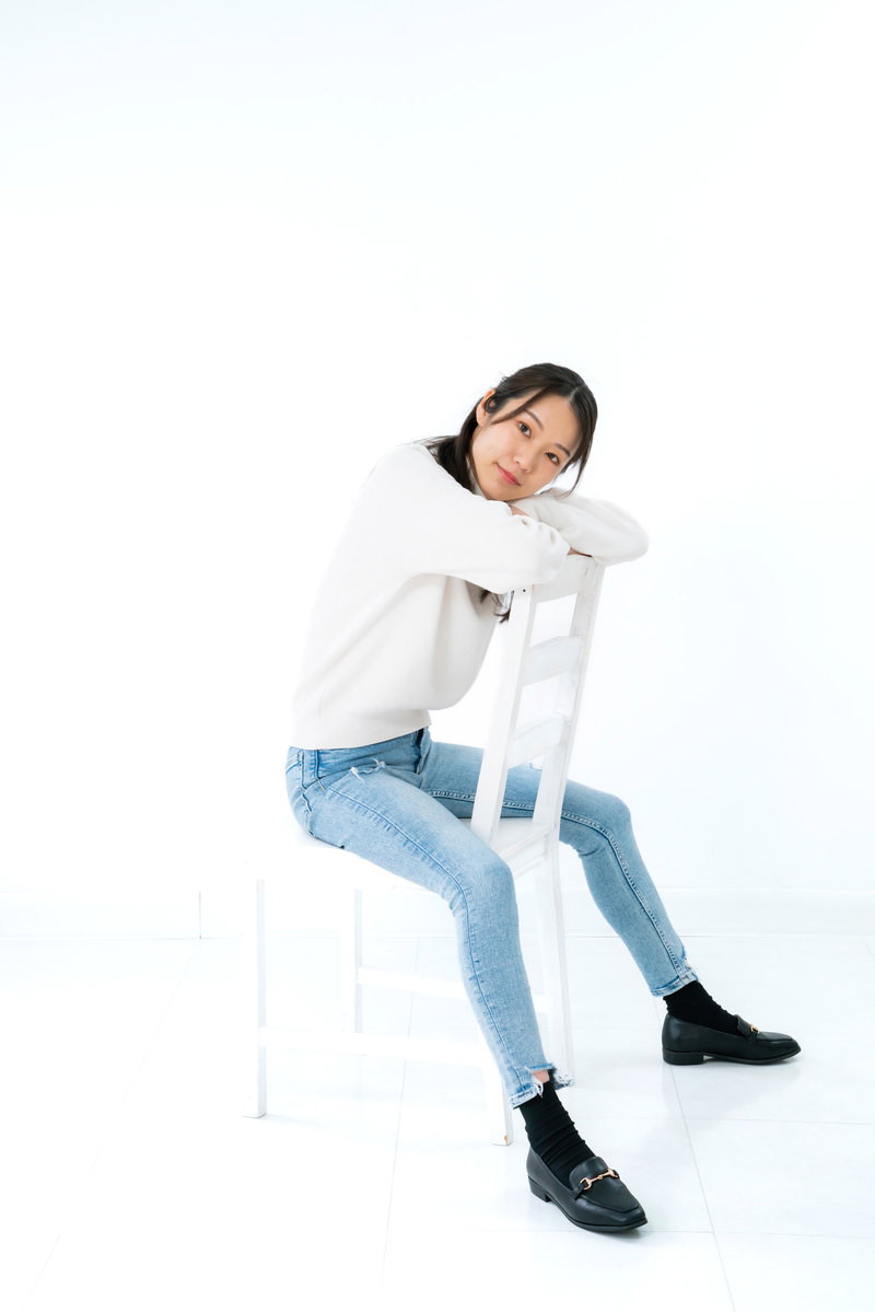 白い椅子に座り疲れた表情を見せる女性［モデル：SAKI］