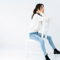 白背景で椅子に腰掛けて振り返る女性のポーズの写真