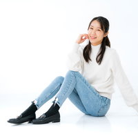 白いニットとデニムで床に座る女性の写真