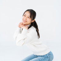 白背景で正座してニッコリ顎のせポーズの女性の写真