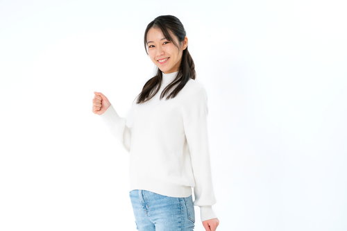 白いセーターで微笑みかける女性、斜め向きで左手を握った上半身ポーズ