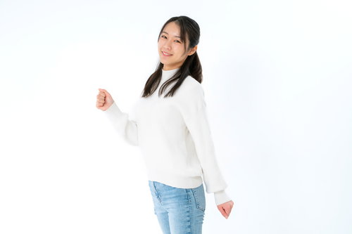 白背景で笑顔で踏み出す女性、白いセーターとジーンズ姿