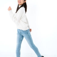 笑顔で歩き出す女性のポーズ、白シャツとデニムパンツのカジュアルスタイルの写真