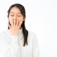 退屈であくびが止まらない白い長袖姿の女性の写真