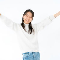 両手を挙げて喜ぶ女性のポーズ、白背景で笑顔の成功表現の写真
