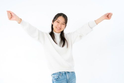 両手を挙げて喜ぶ女性のポーズ、白背景で笑顔の成功表現