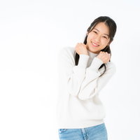 白いニットを着て笑顔でぶりっ子ポーズをする女性の写真