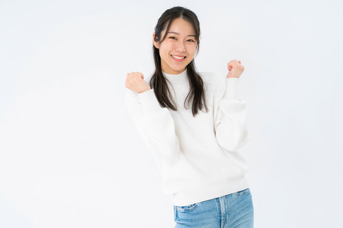 白背景で小さくガッツポーズして笑顔の女性