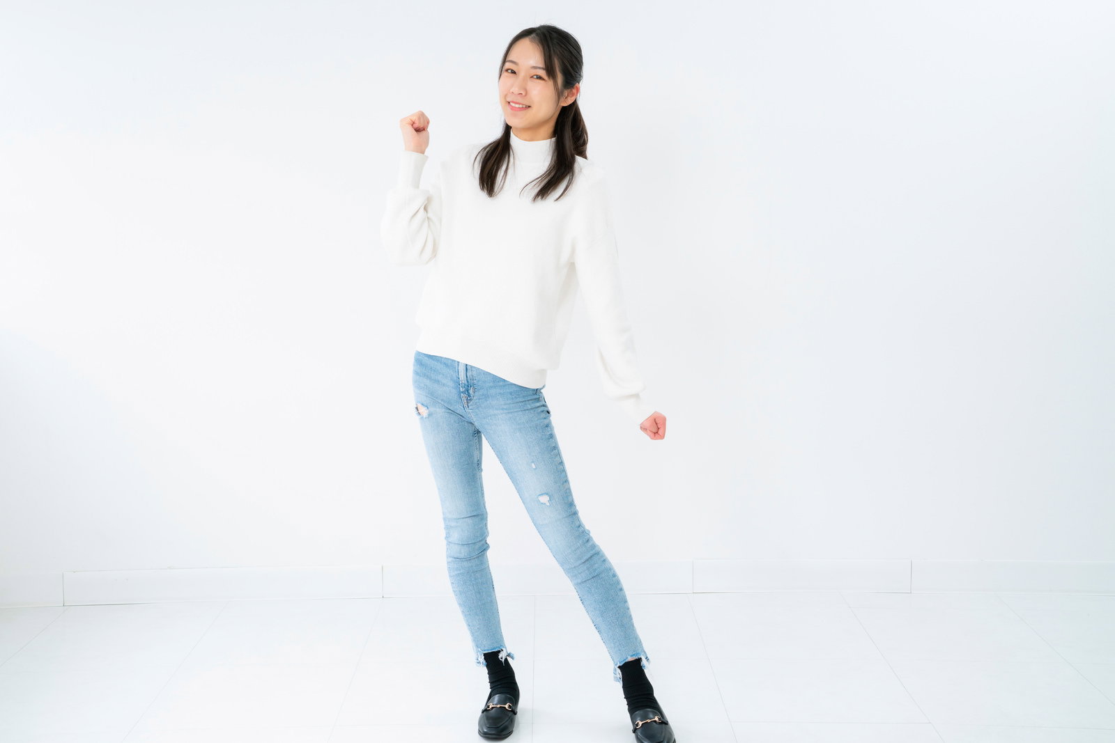 白いトップスを着た女性がガッツポーズを決めて笑みを浮かべている［モデル：SAKI］