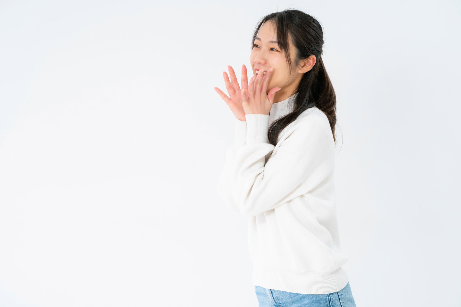 耳打ちする白いニット姿の女性が秘密を伝える仕草をしている［モデル：SAKI］