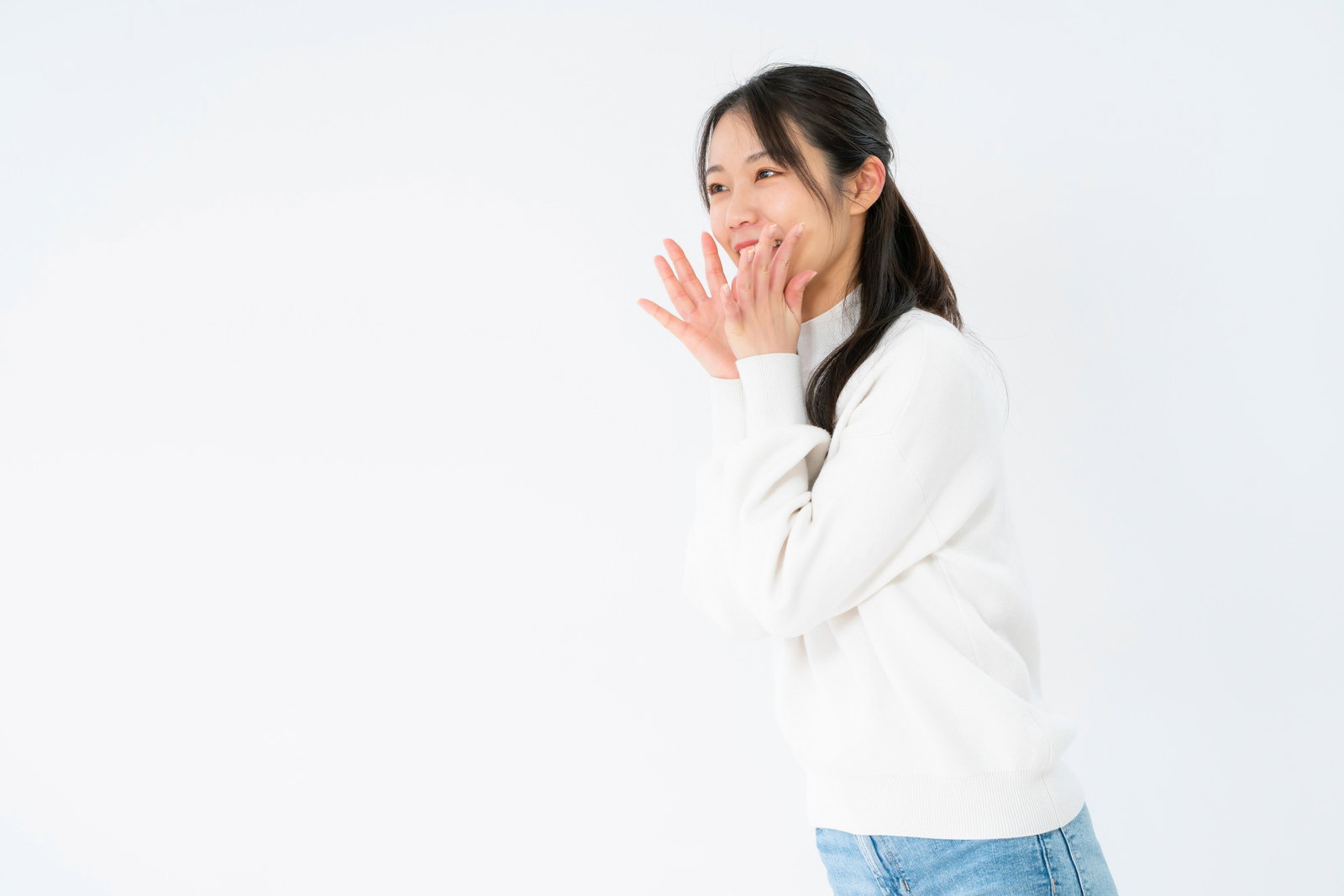 白いシャツを着た女性が両手を口に添えて応援している［モデル：SAKI］