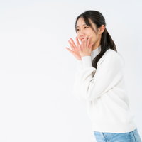 両手を口に添えて応援する白シャツの女性のポーズの写真