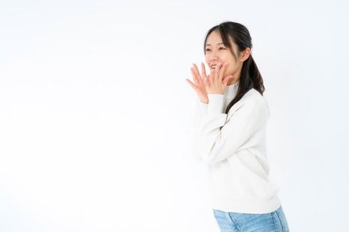 両手を口元に当てて大きな声でアピールする女性