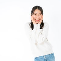 白背景に頬に手を添える笑顔の女性のポートレートの写真