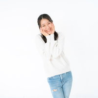 両手で頬を包み込んで笑顔を見せる女性の写真