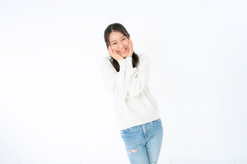 両手で頬を包み込んで笑顔を見せる女性