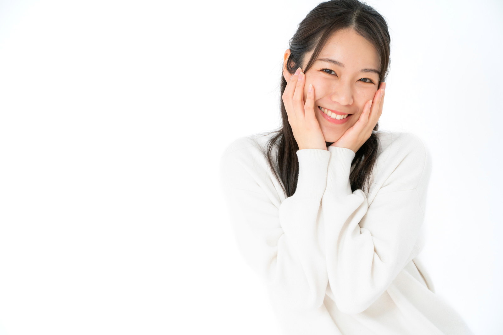 白い服を着た女性が頬に両手を添えて笑顔を向ける［モデル：SAKI］