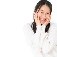 満面の笑みで頬に手を添える女性のポートレートの写真