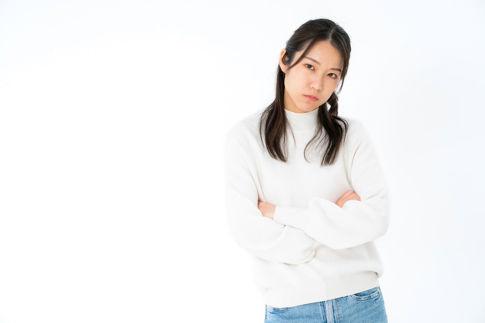 白いニットを着て腕を組み、ご機嫌ななめで不機嫌な表情の女性［モデル：SAKI］