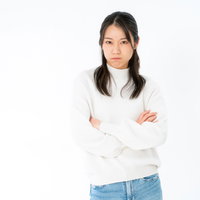 白いタートルネックで腕組みする不機嫌な表情の女性の写真