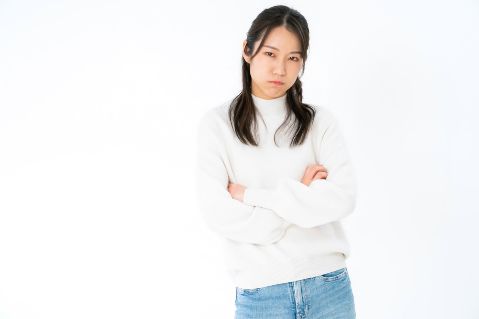 白いニットを着た女性が腕を組んで怒った表情を見せているポーズ［モデル：SAKI］