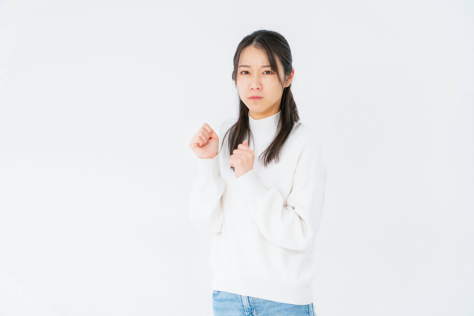 両拳を握っていじける白いニット姿の女性［モデル：SAKI］