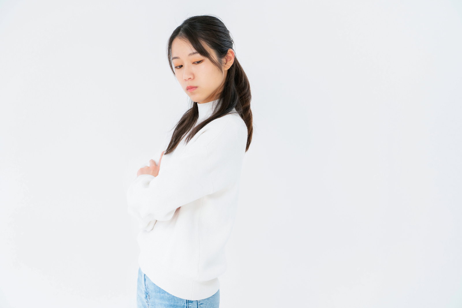 白いシャツを着た女性が腕を組んで目をそらしている［モデル：SAKI］