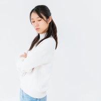 腕を組んで目をそらす女性のポーズ、不機嫌な表情の写真