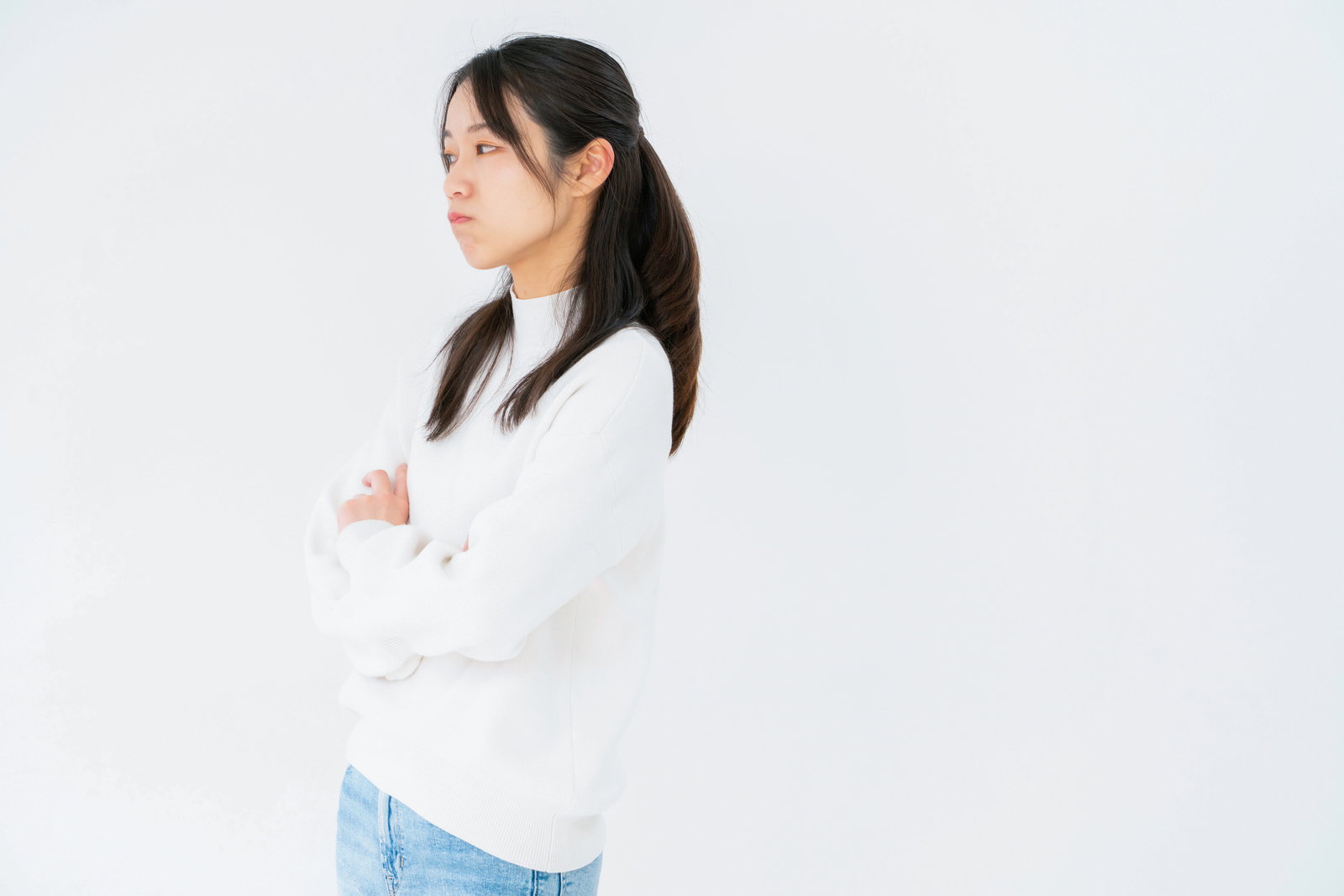 白いニットを着た女性が腕組みしてそっぽを向いている［モデル：SAKI］