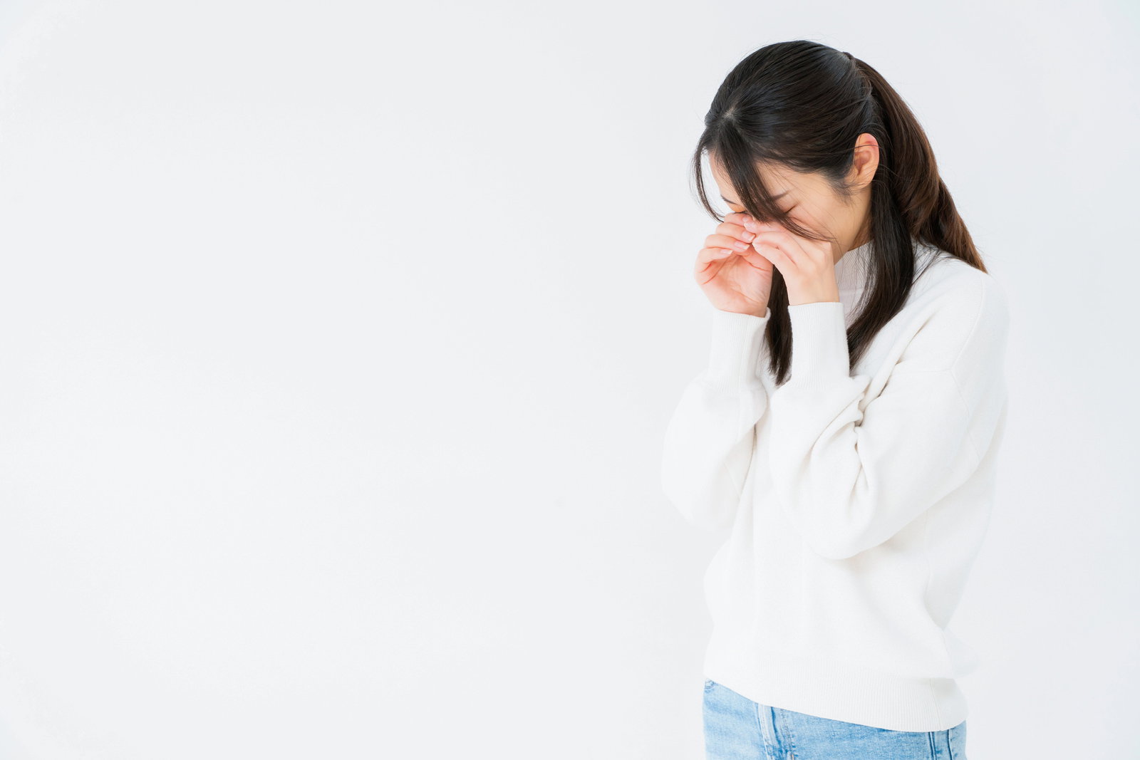 白背景で両手で顔を覆いながらめそめそする女性のポーズ［モデル：SAKI］