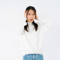 両手で頭を抱えて混乱する女性の写真