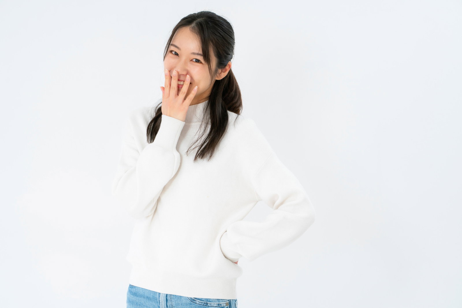 口元を手で隠してはにかみながら笑う女性が白背景でポーズをしている［モデル：SAKI］