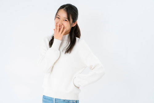 口元を手で隠してはにかみながら笑う女性のポートレート