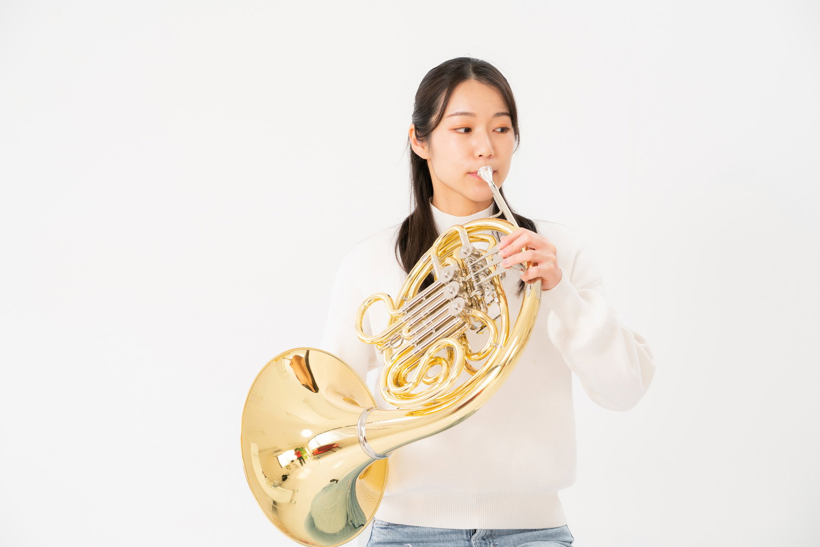 ホルンを口に当てて演奏する女性の正面姿［モデル：SAKI］