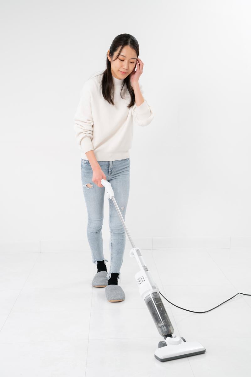 スマートフロアクリーナーで床を掃除する女性が下を向いて作業している［モデル：SAKI］